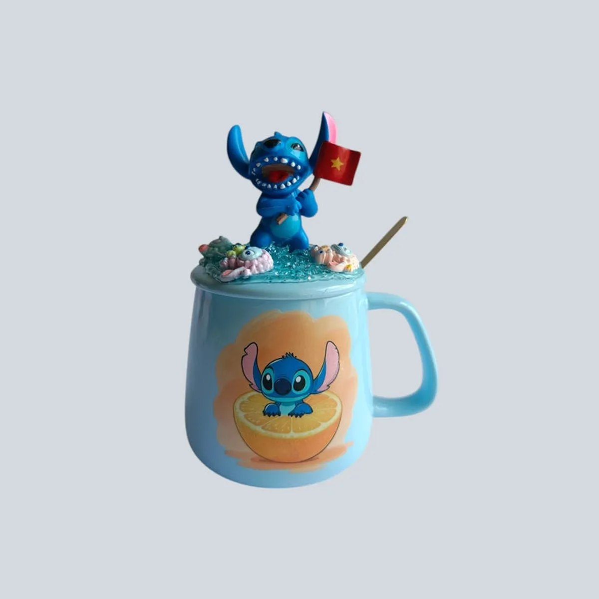Blue Stitch mug with decorative lid and spoon on plain background