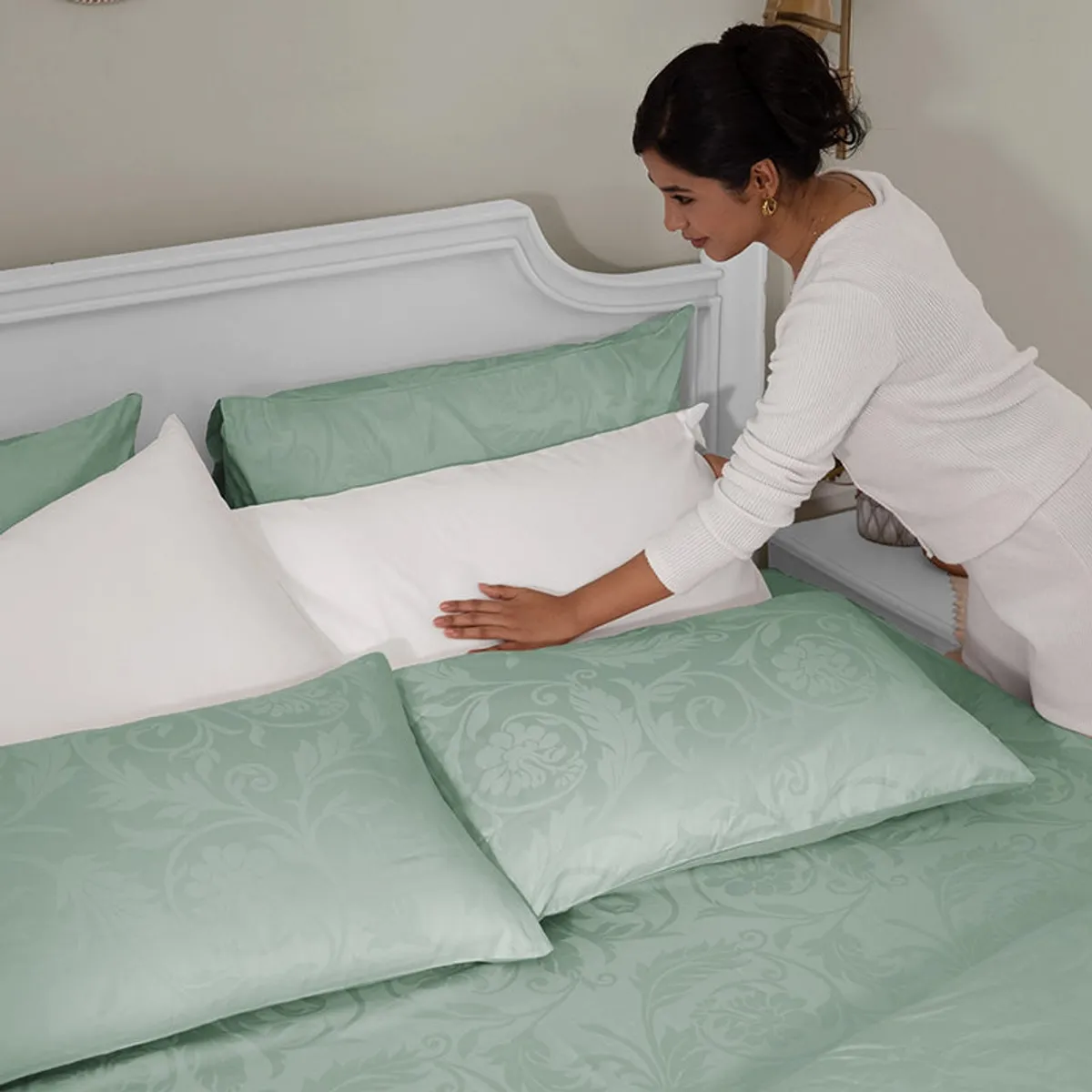 Sage green floral duvet cover being arranged on a bed