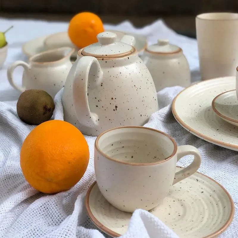 Close view of a white speckled ceramic teapot, cup and saucer set