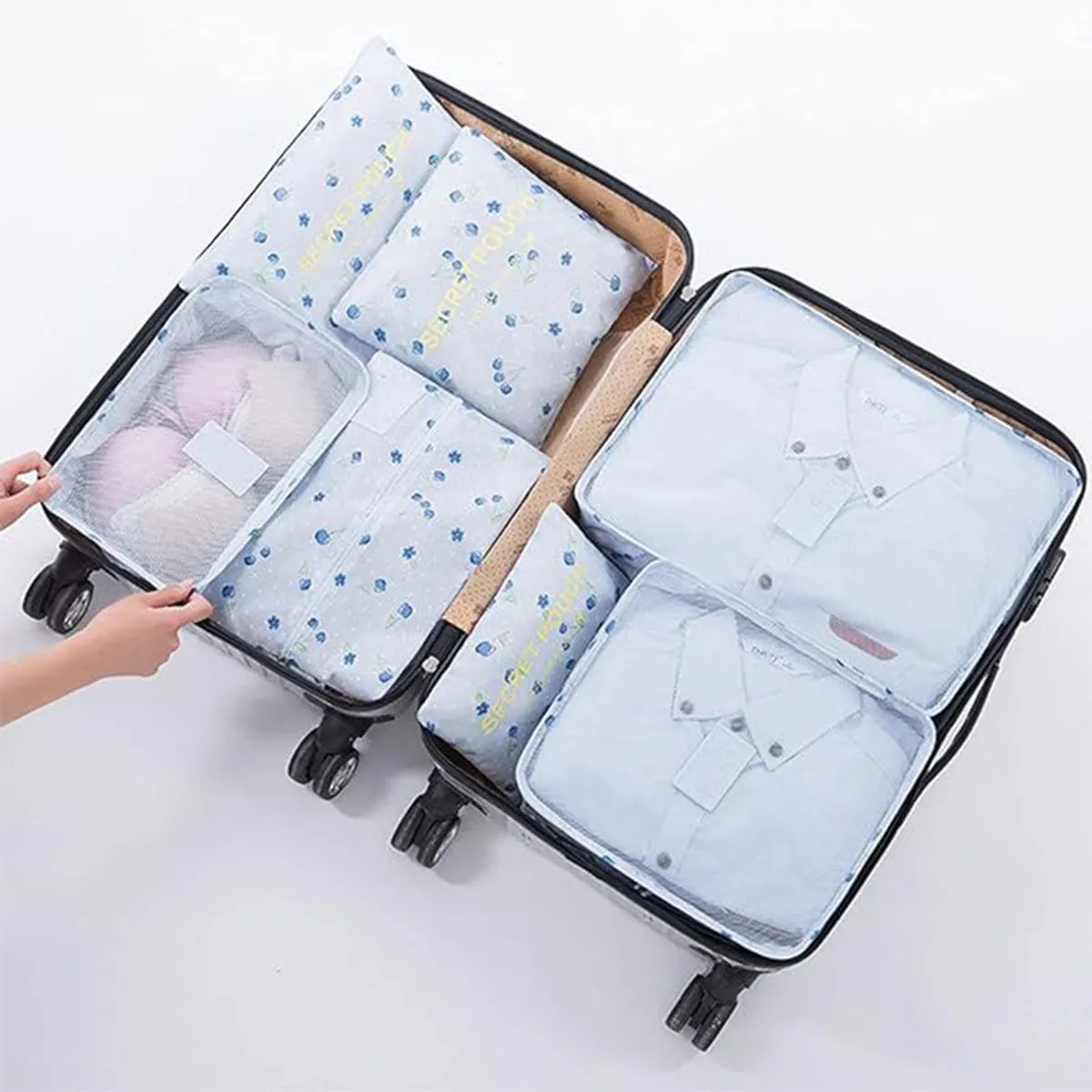 Open suitcase showing blue floral organisers filled with folded clothing.