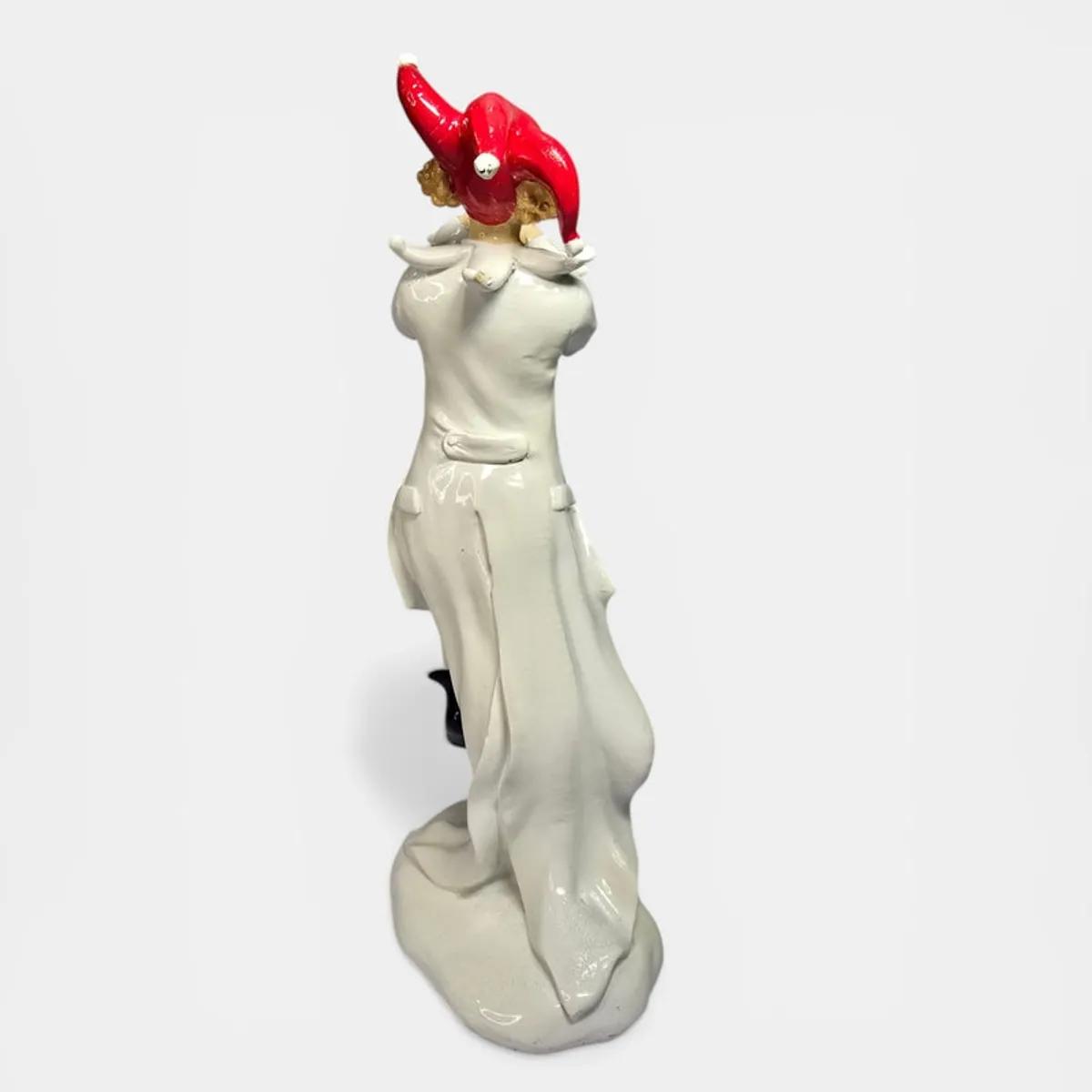 Back view of glossy clown figurine with red hat and flowing coat