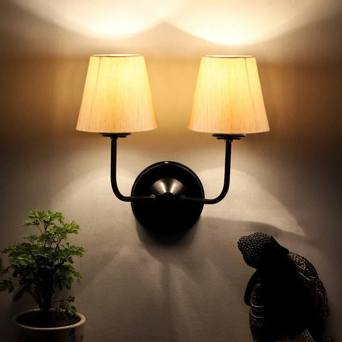 Lit twin beige wall lamp casting warm upward light on the wall