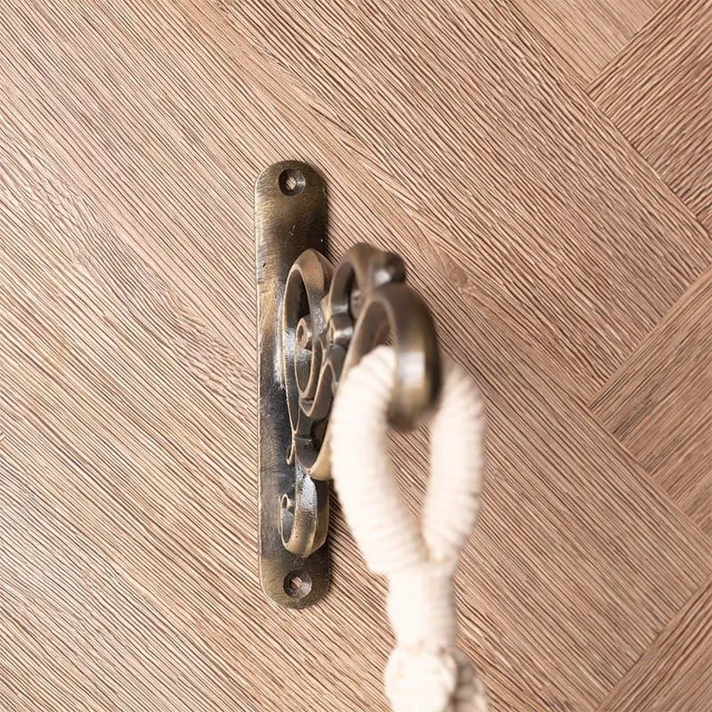 Side view of a copper scrollwork wall bracket mounted on a wood surface