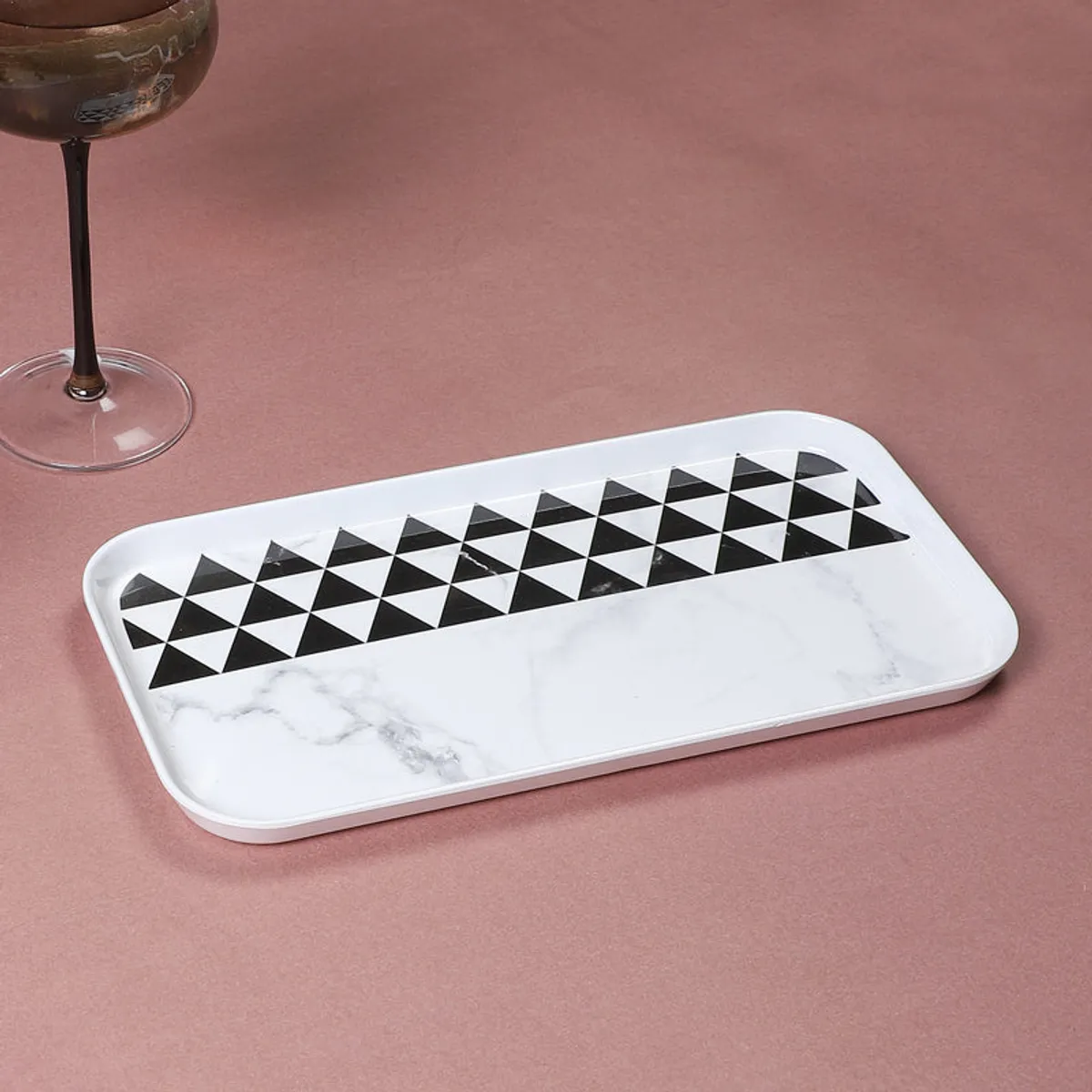 Rectangular black-and-white geometric serving tray shown from above on a pink surface