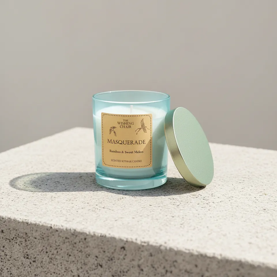 Aqua glass candle with lid leaning beside it on a stone plinth