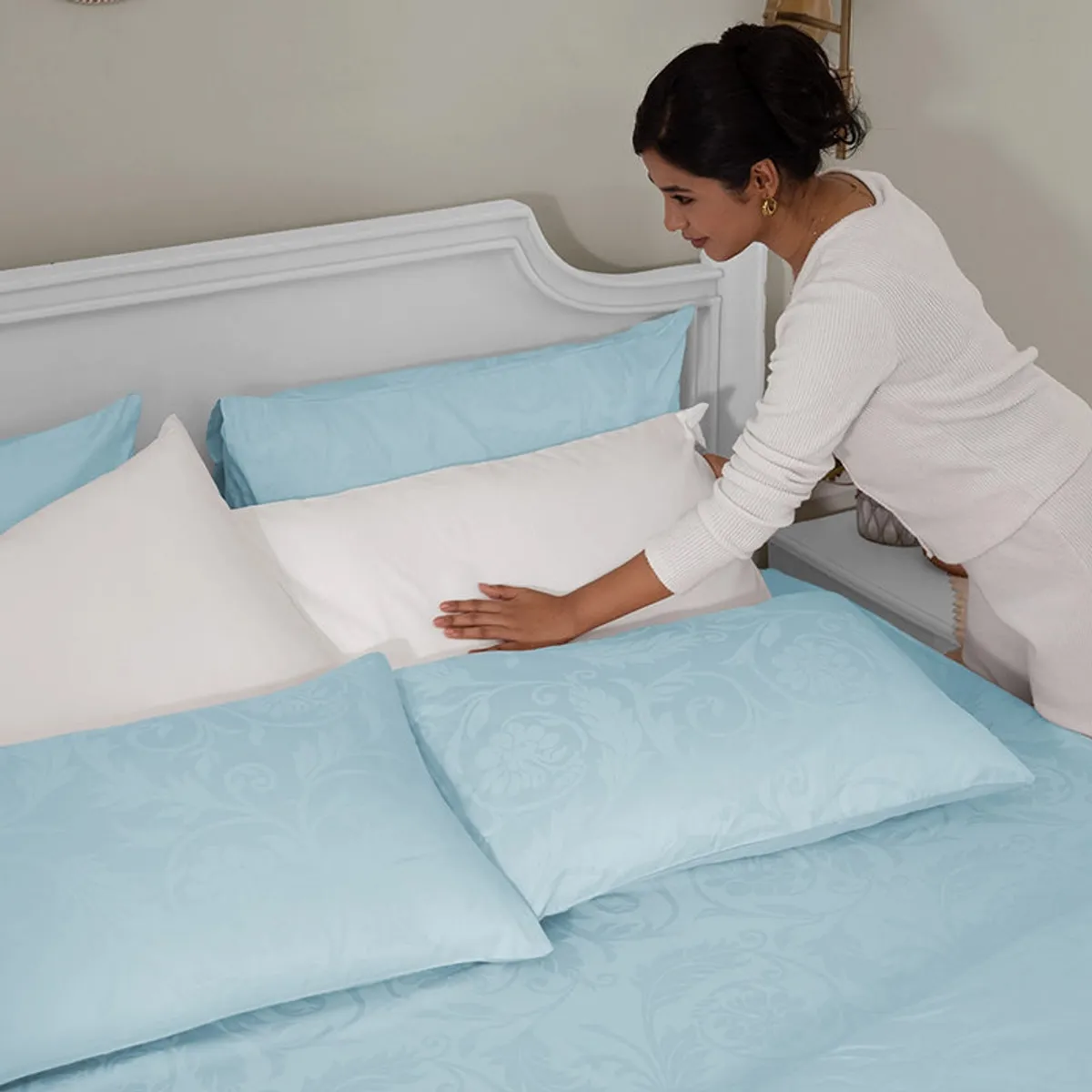 Pale blue floral duvet cover being arranged on a bedroom bed