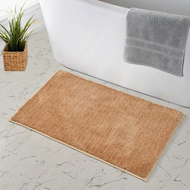 Beige bath mat positioned beside a white bathtub