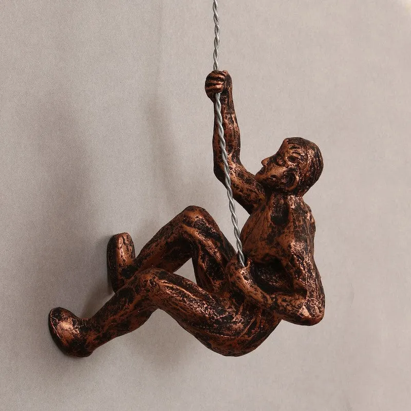 Bronze climbing figure wall accent displayed on a plain wall