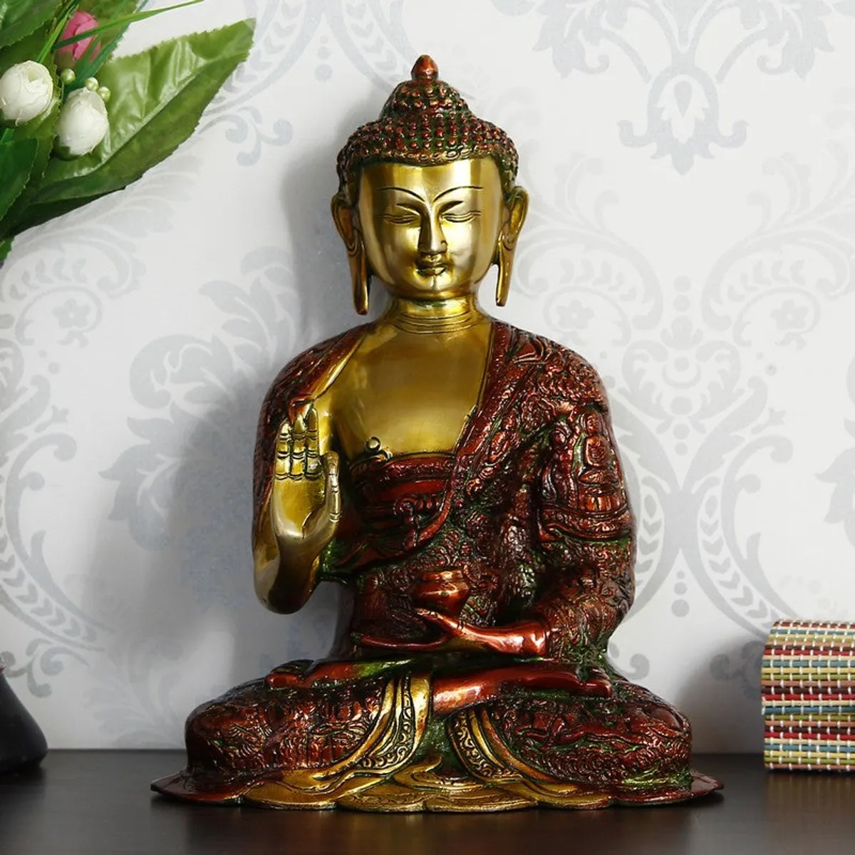 Buddha brass idol placed on a tabletop against patterned wallpaper
