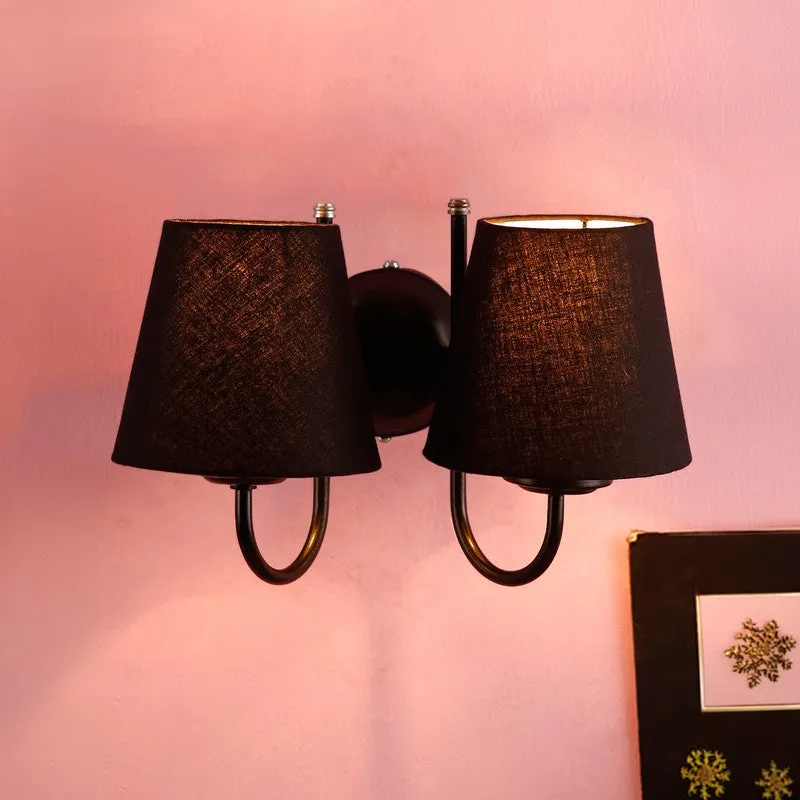 Twin black wall lamp shown lit against a pink wall