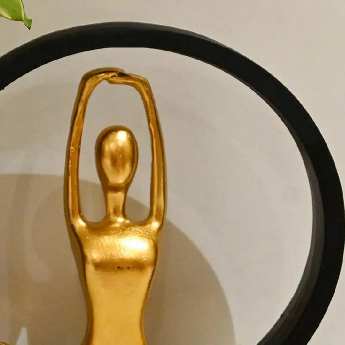 Close-up of the gold yoga figurine within the black circular frame