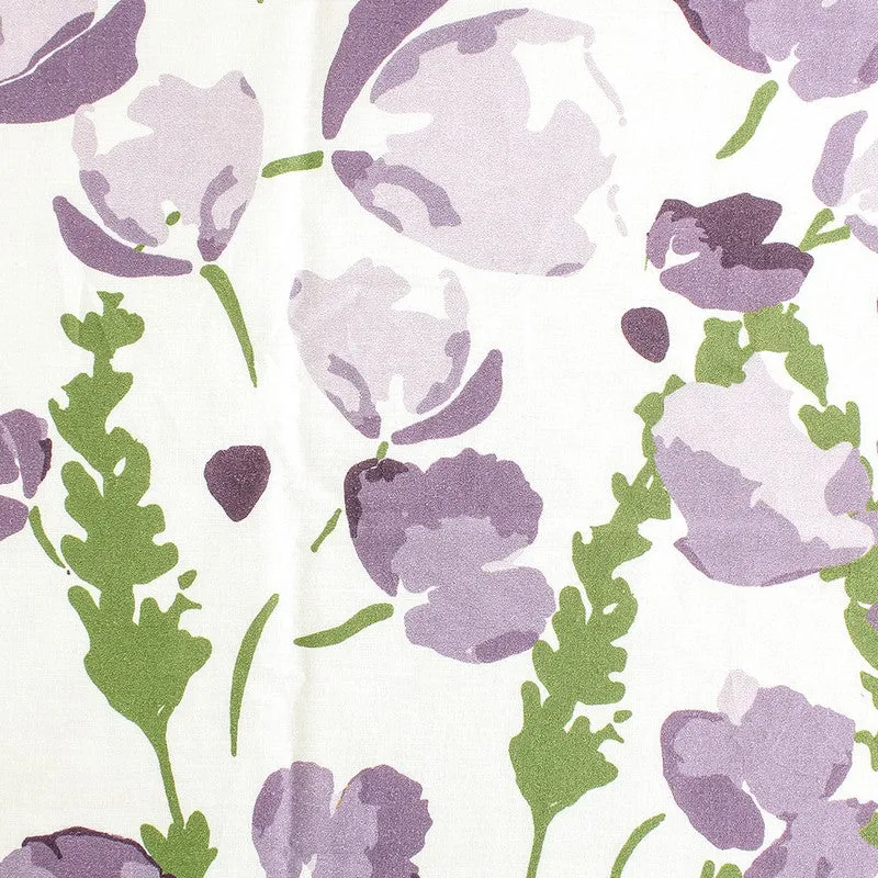 Detailed view of purple flowers and green leaves on white fabric