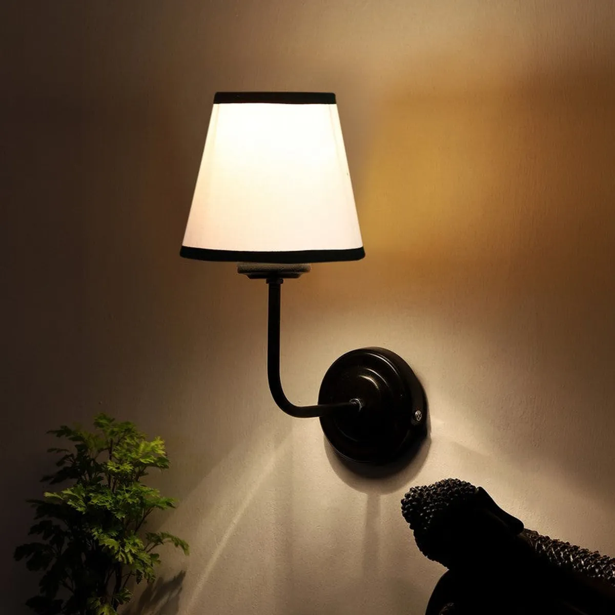 Warm glowing wall lamp with white shade and black iron base