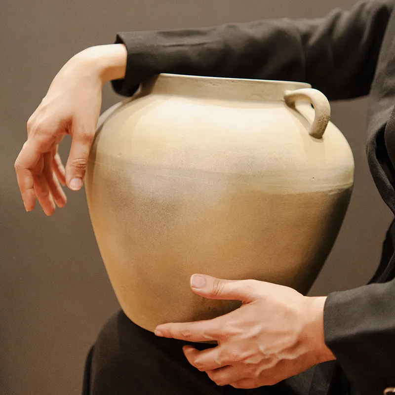 Large beige ceramic vase being held to show scale