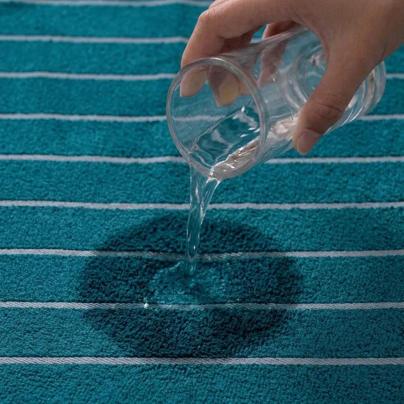 Water being poured onto a blue striped bath towel