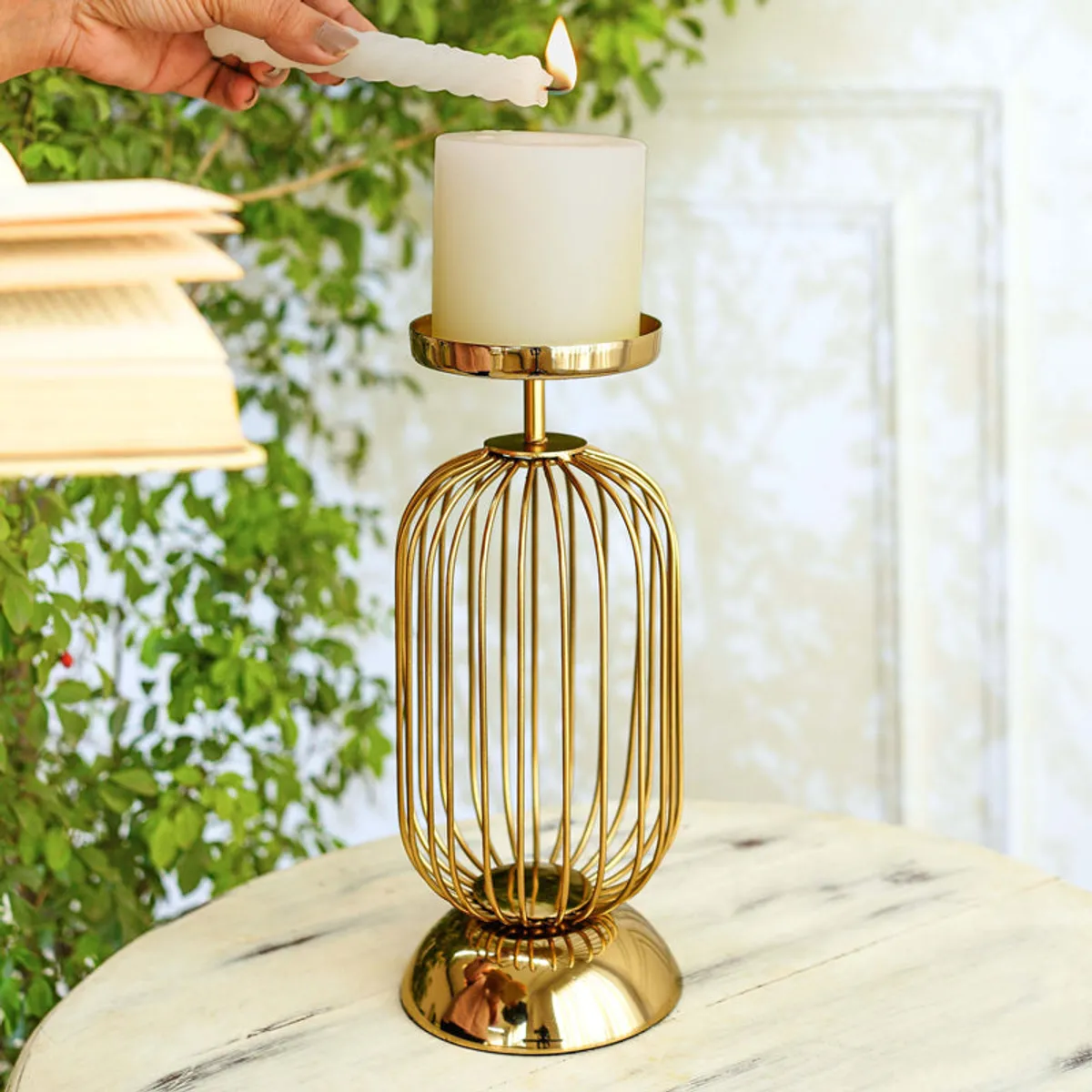 Gold wire cage candle holder with a lit white candle