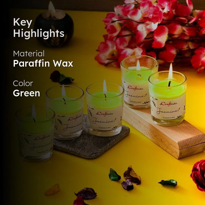 Five green jasmine candles arranged on boards and a stone tray beside flowers