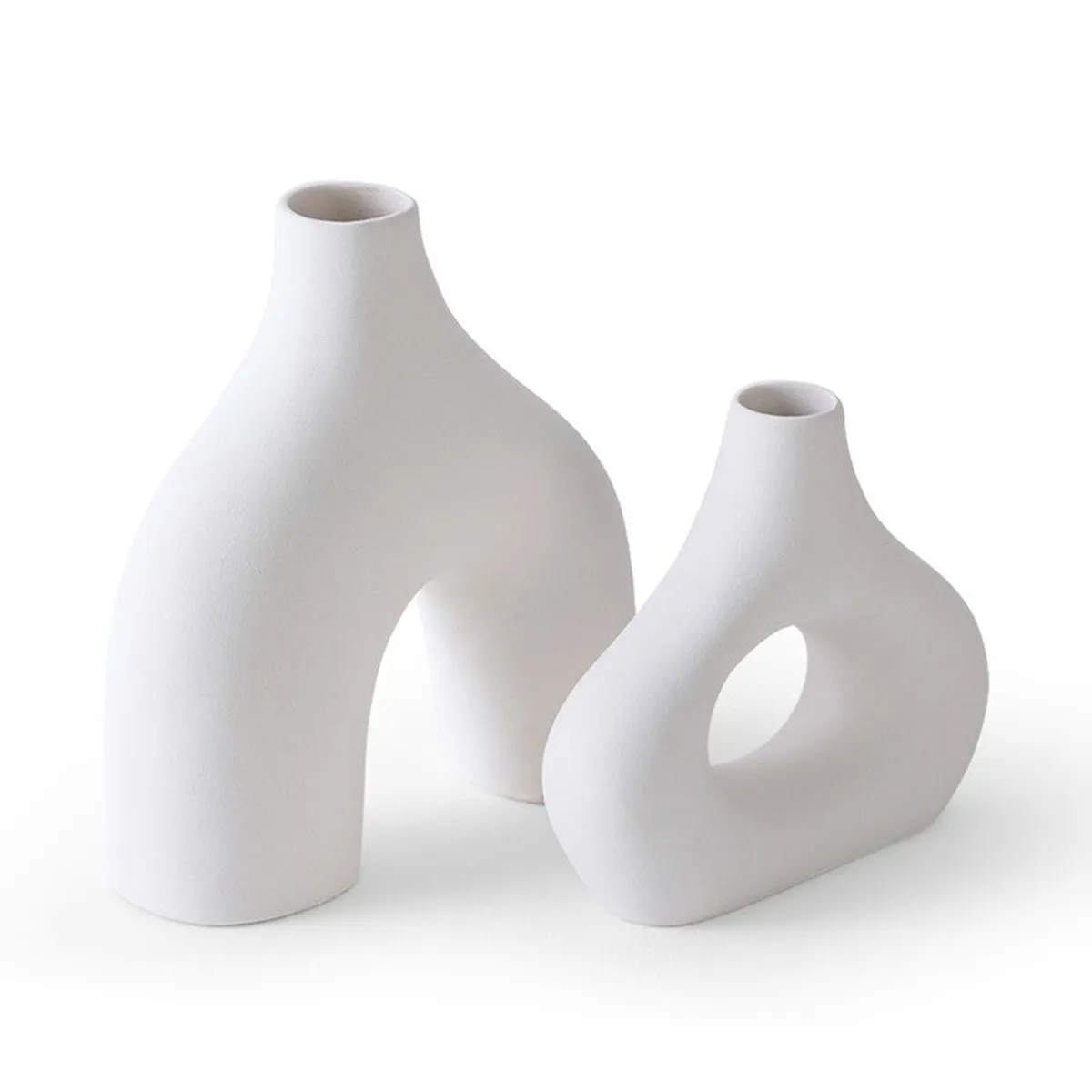 Pair of white sculptural ceramic vases on a plain white background.