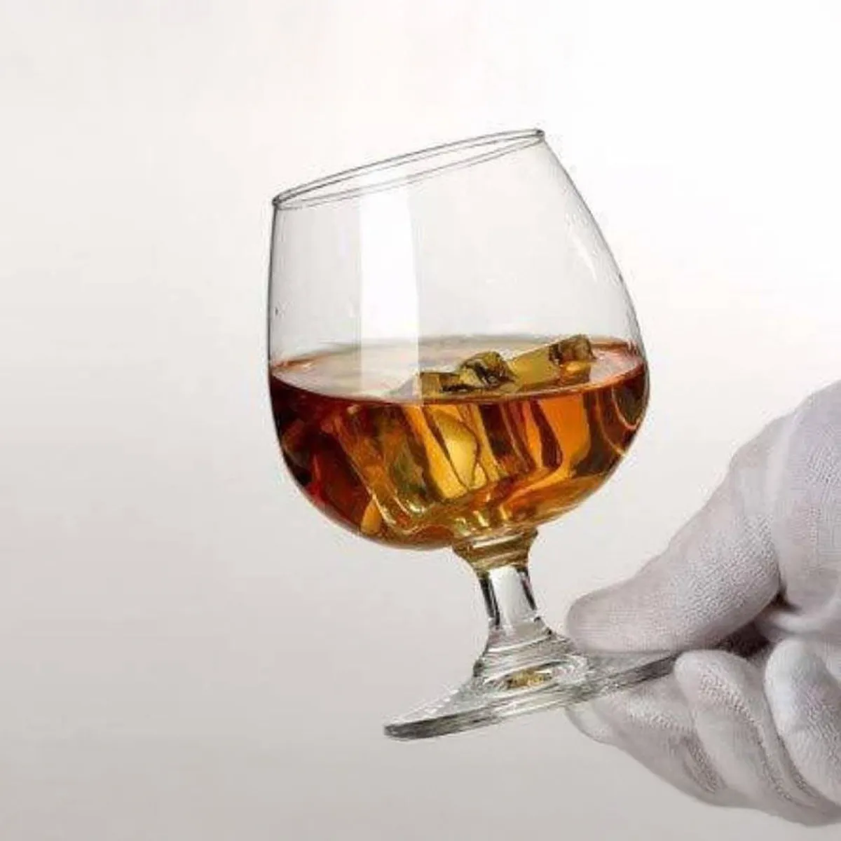 Rounded clear glass with amber drink held at an angle