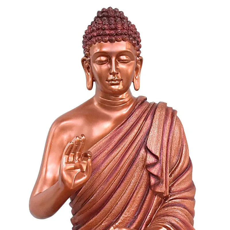 Close-up of the Buddha idol with copper and pink-toned draped robe