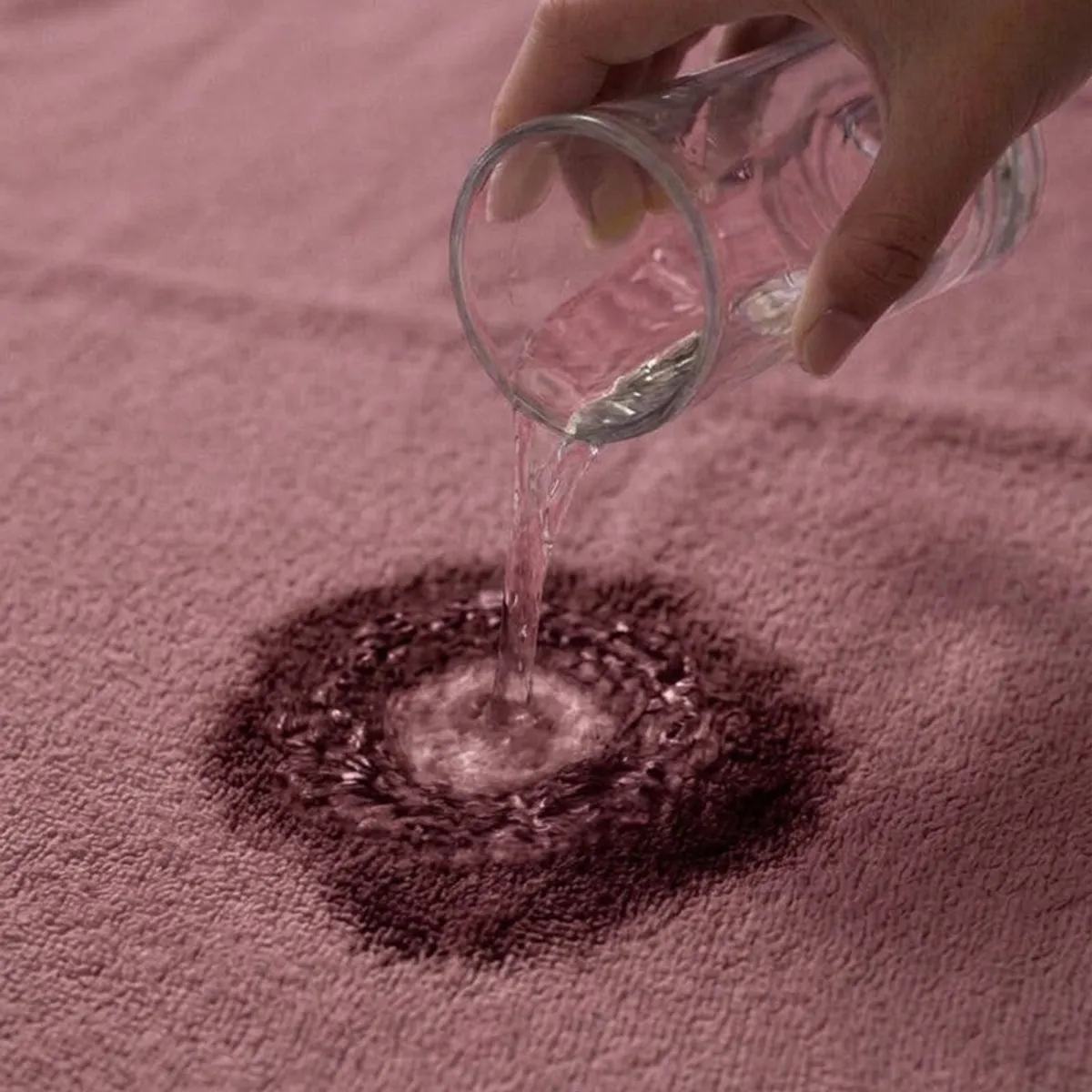 Water being poured onto the absorbent dusty pink towel surface
