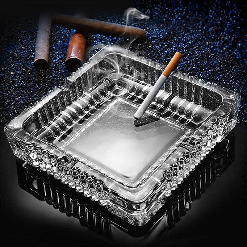 Transparent square glass ashtray with ribbed edges and a cigarette inside