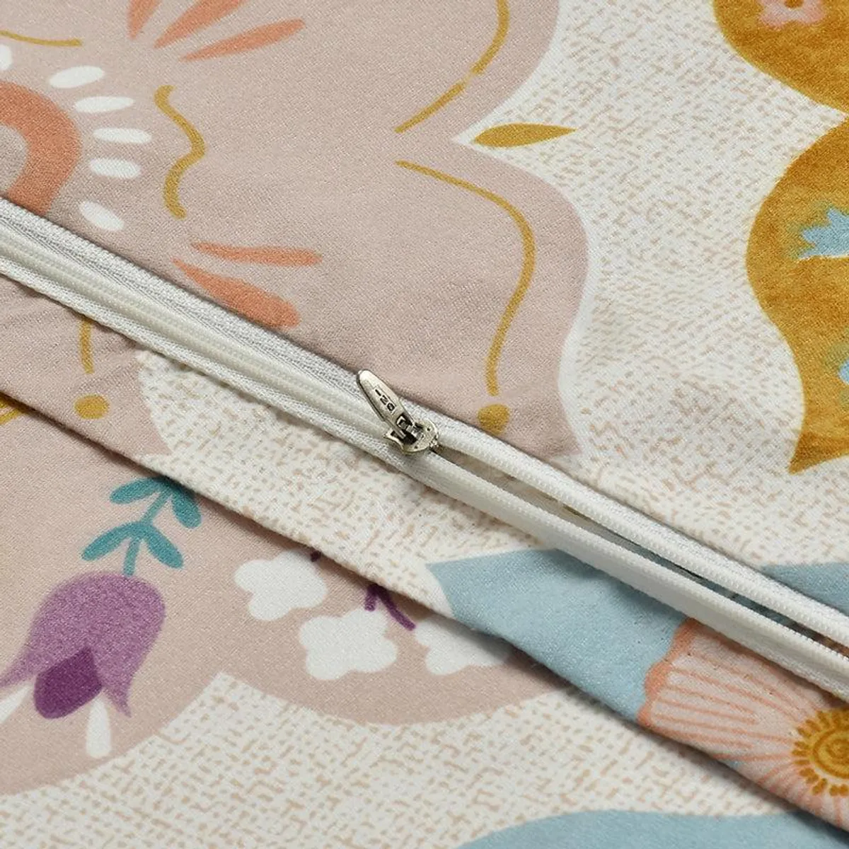 Close-up of the duvet cover's colourful printed cotton pattern and zip