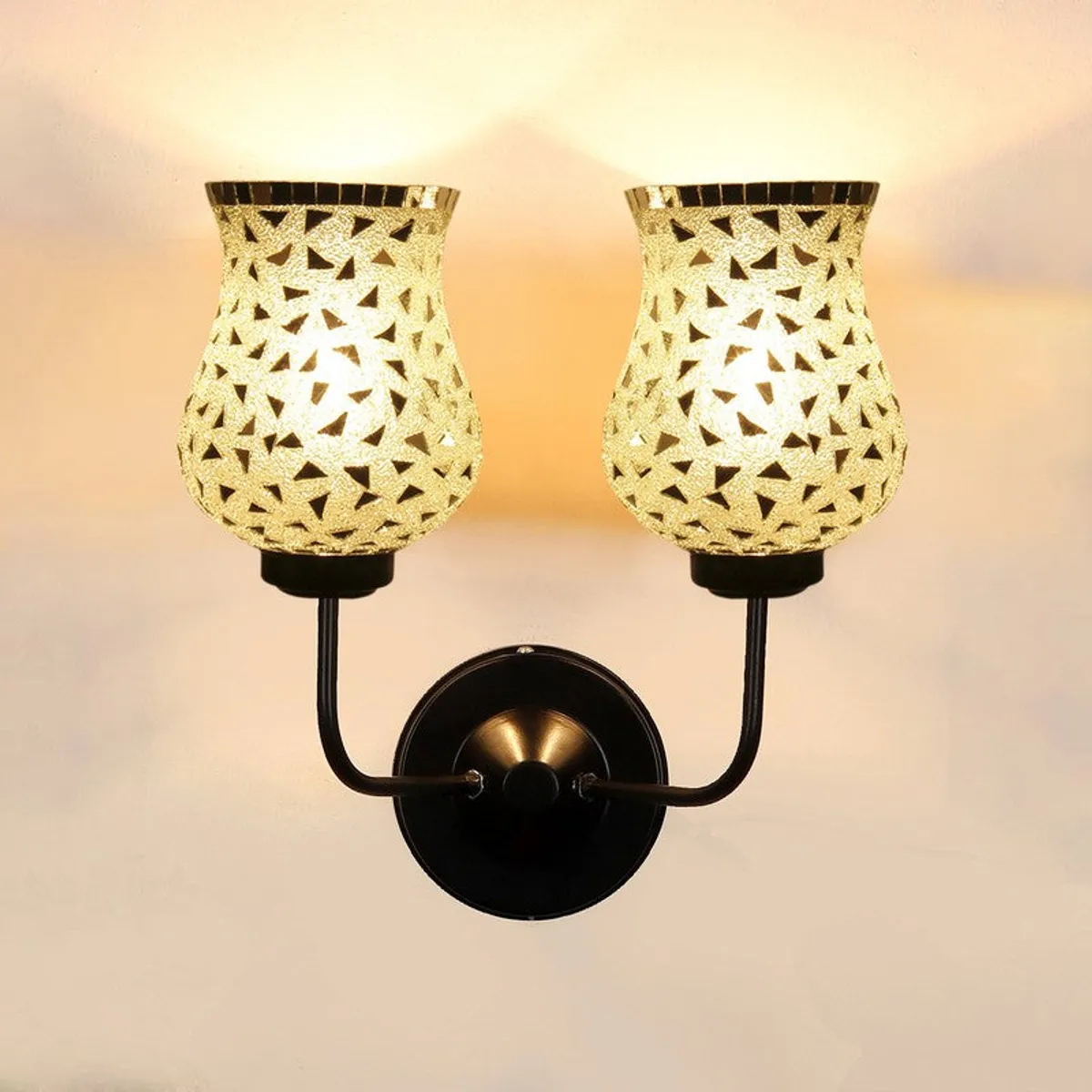 Close view of lit double-shade mosaic wall lamp with black iron arm