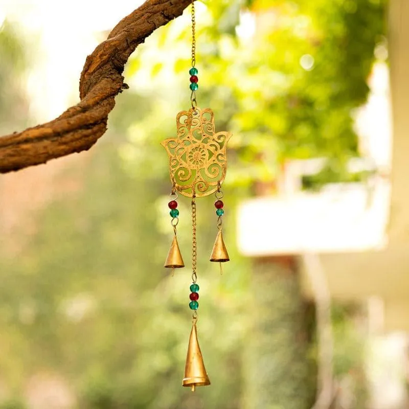 Gold Hamsa windchime hanging from a tree branch outdoors