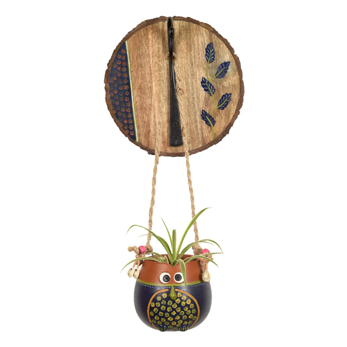 Owl-shaped hanging planter with a round decorated wooden wall plate and green plant.