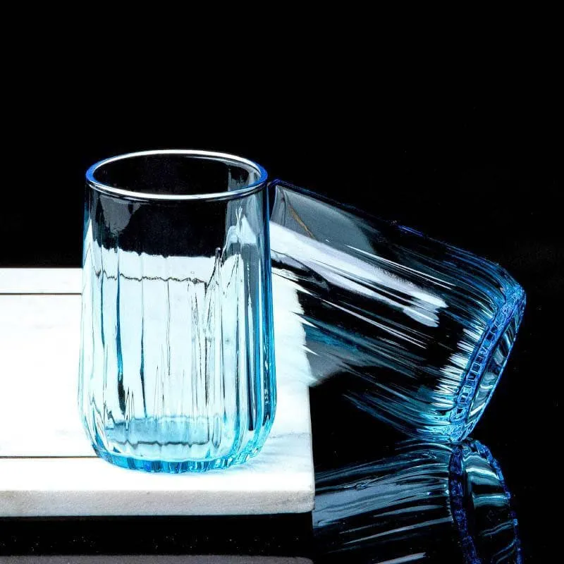 Two blue ribbed glass tumblers on a black reflective surface