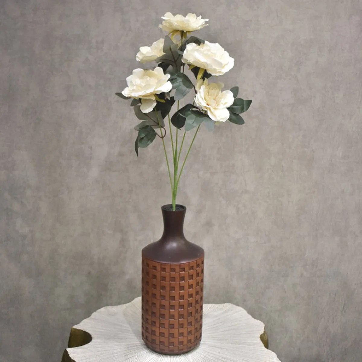 Artificial off-white peony arrangement shown in a brown pot against a grey wall