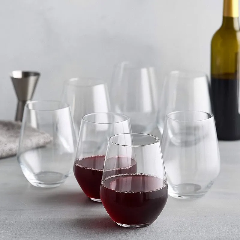 Six clear stemless glasses with red wine on a light surface