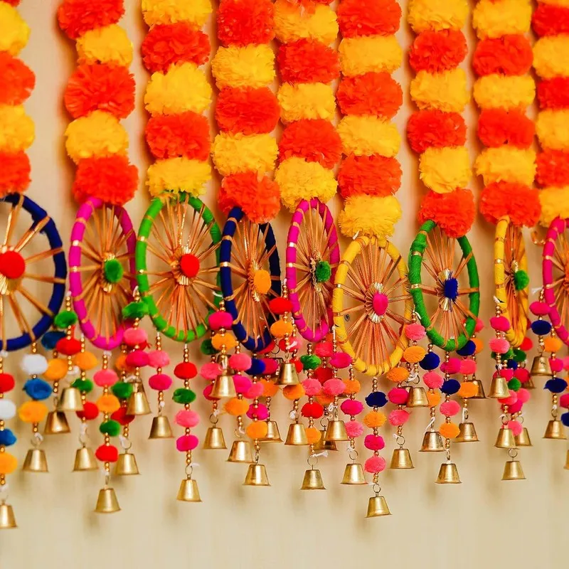 Close-up of colourful chakra details and hanging bells beneath marigold strands