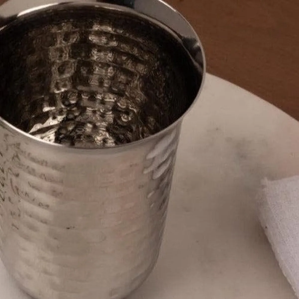 Detailed view of the glossy hammered texture on a silver drinking glass