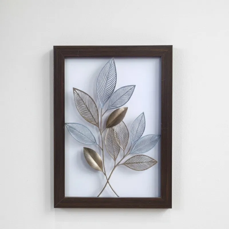 Close-up of a framed botanical leaf wall art piece with blue and metallic tones
