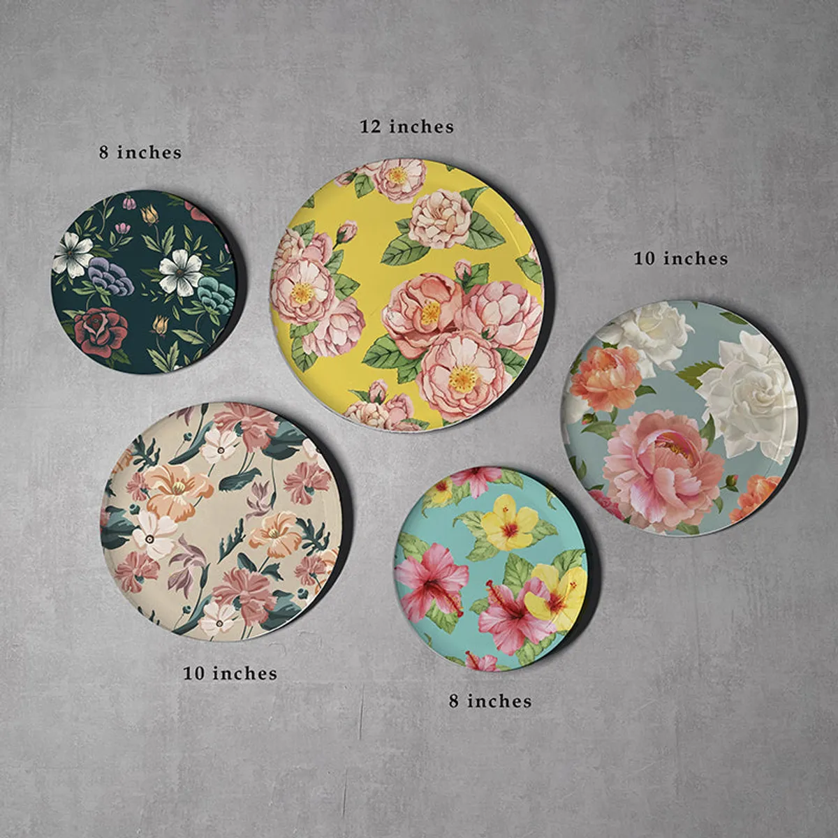 Five round floral wall plates in assorted sizes on a wall