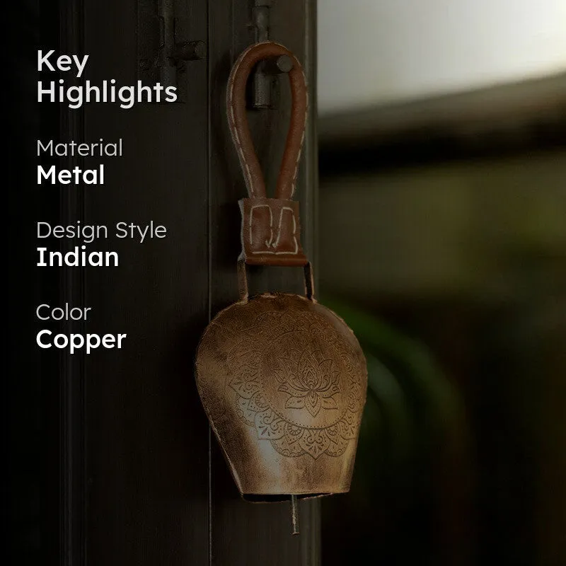 Copper hanging bell displayed on a dark doorway in a lifestyle setting.