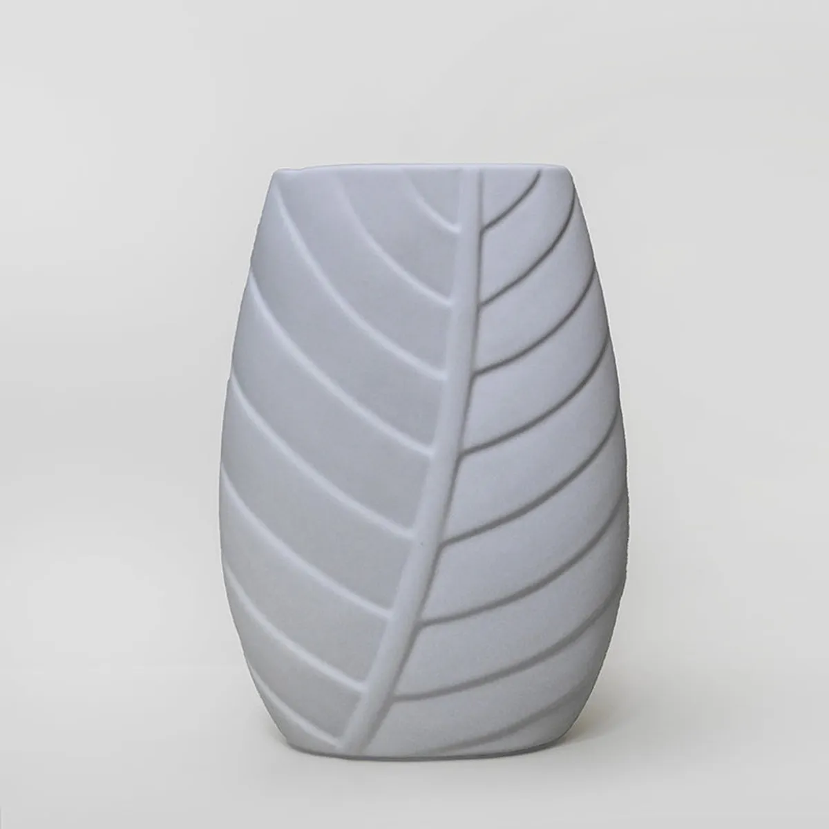 Front view of a white vase with embossed leaf pattern on a plain background