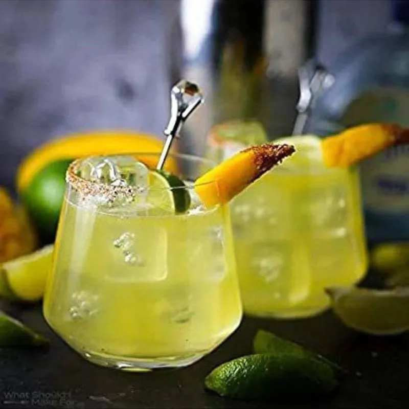 Clear tumbler filled with a pale citrus cocktail, ice and an orange garnish.
