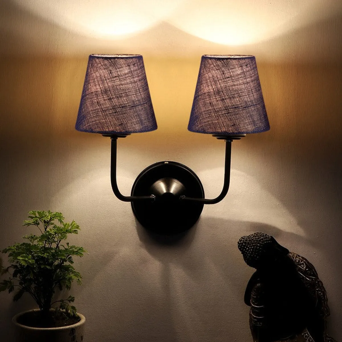 Lit blue twin-shade wall lamp casting upward glow on the wall