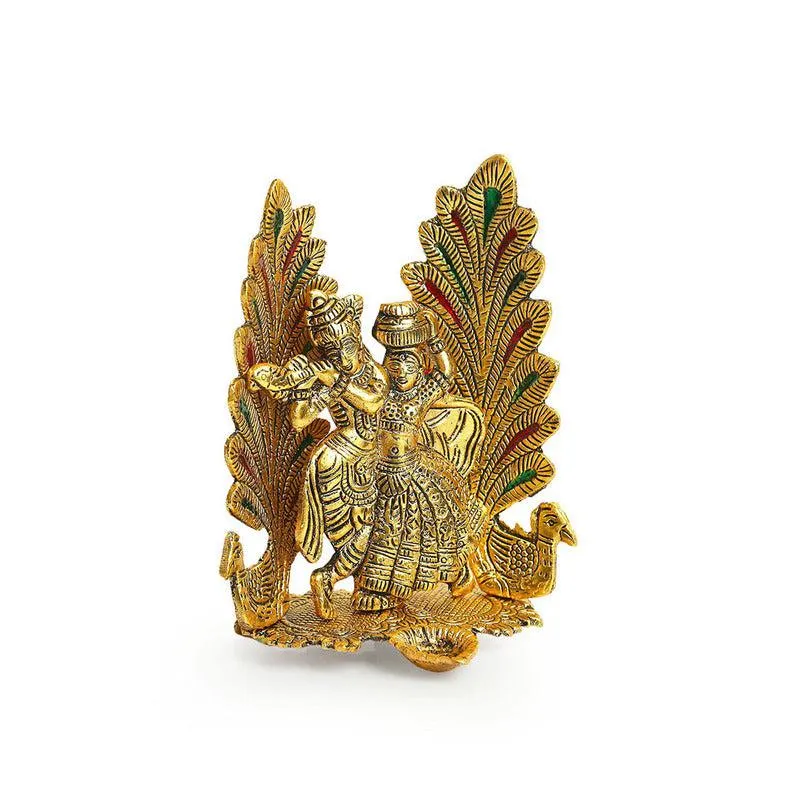 Angled view of a gold-toned Radha Krishna diya showpiece on a white background