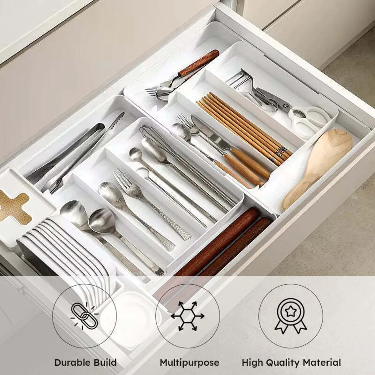 White cutlery organiser filled with assorted utensils inside a kitchen drawer