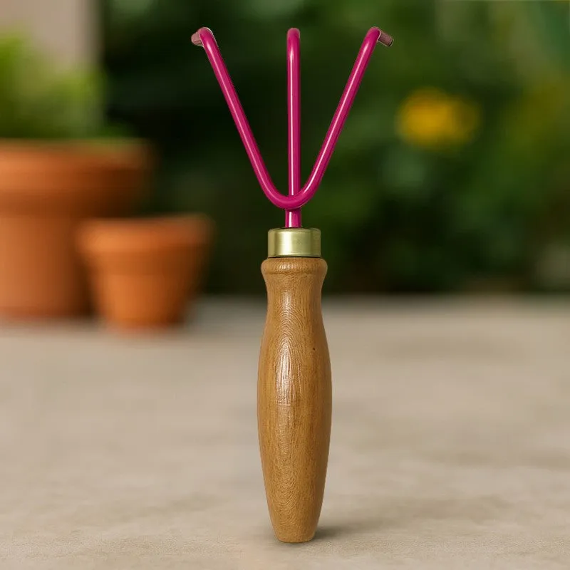 Pink three-pronged garden cultivator standing upright with its wooden handle visible.