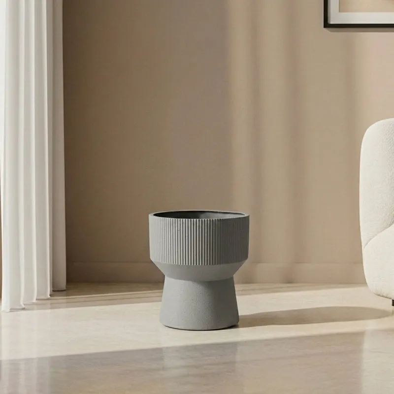 Small grey ribbed planter standing on a sunlit indoor floor
