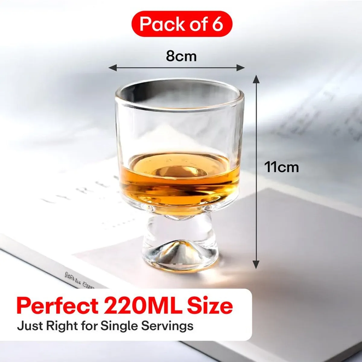 Single clear footed glass with amber drink on a light surface