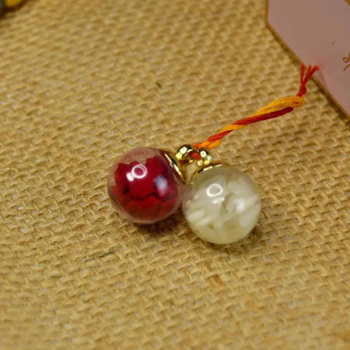 Close-up of red and cream decorative beads tied with orange and yellow thread.