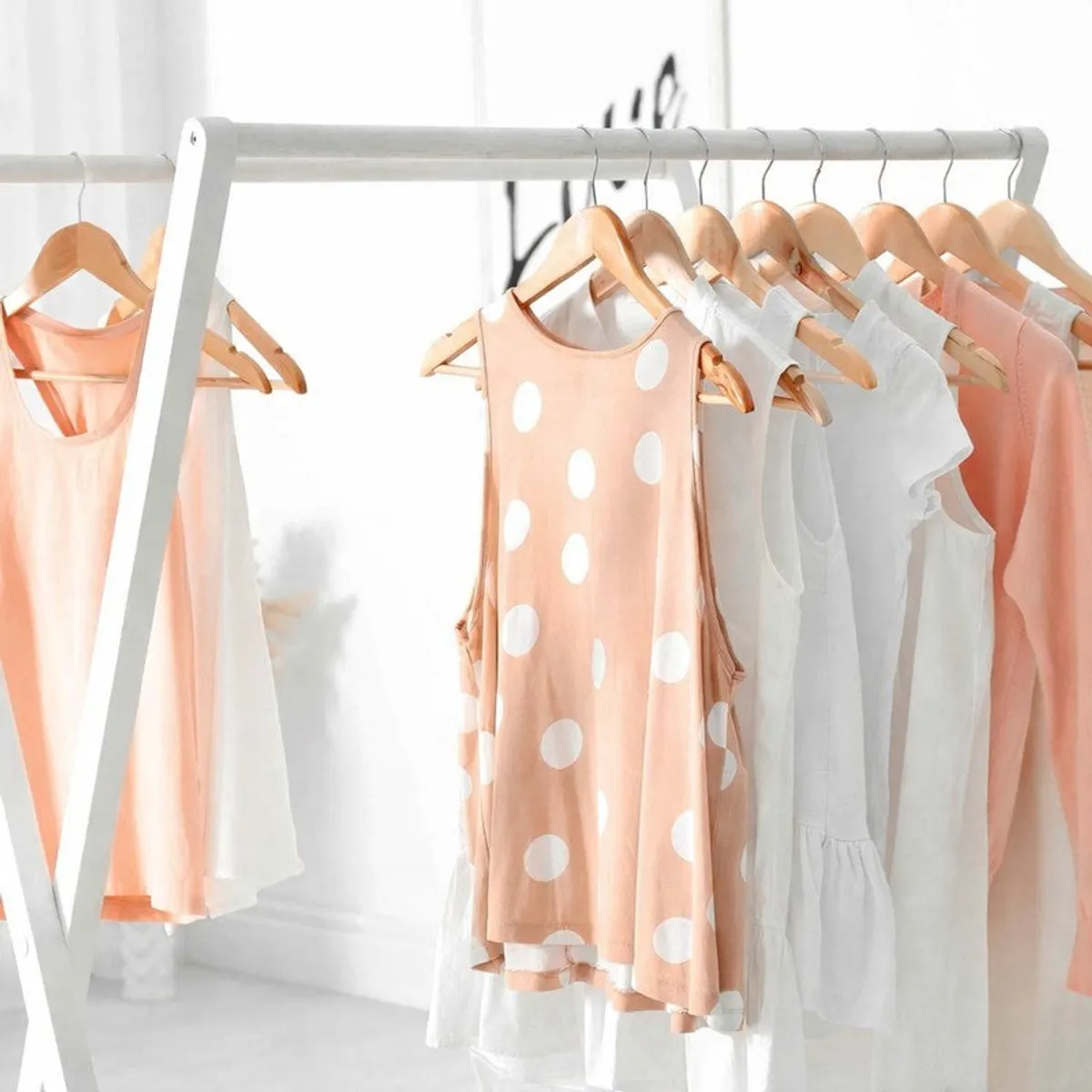 Wooden hangers displaying pastel and white garments on a rack