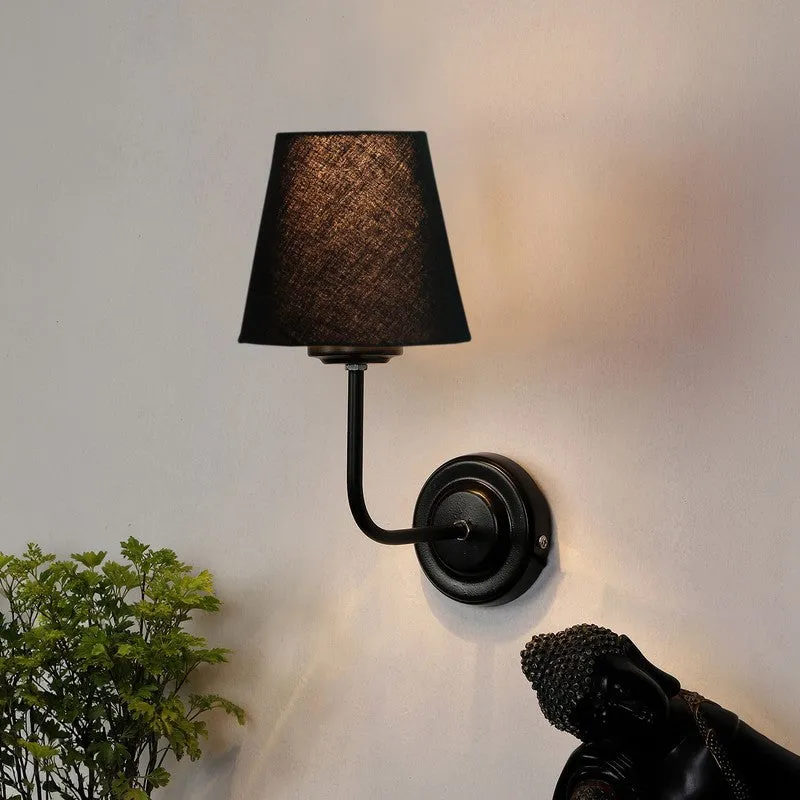 Lit black wall lamp with textured shade and curved iron arm