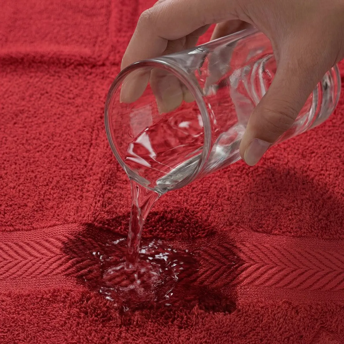 Water being poured onto the absorbent red bath towel
